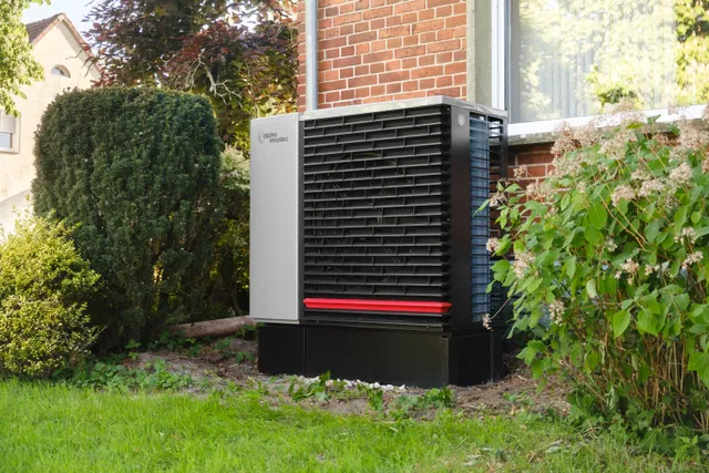 Wärmepumpe im Garten neben einem Wohnhaus